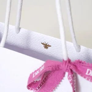 有名コスメブランドの純白ボディに映える、高級感のある箔押しロゴとピンクリボンが可愛いオリジナル紙袋