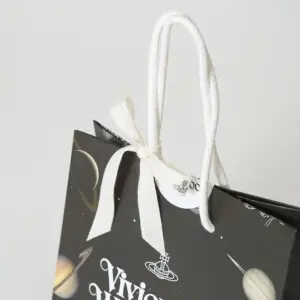 ブランドロゴがプリントされたリボンがハンドルに巻きつけ、ギフト感を強めた、イギリス発アパレルブランドの神秘的でロックなオリジナル紙袋