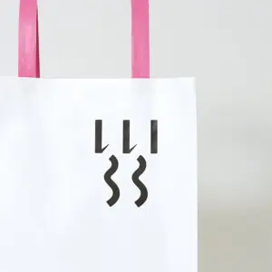 シンプルな縦留めのハンドルを採用した、食と雑貨のセレクトショップのオリジナル紙袋