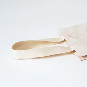 コットン素材のハンドルが縦留め加工された、ジュエリーブランドのエレガントなオリジナル紙袋