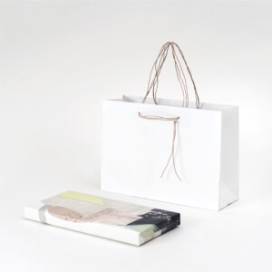 清潔感のあるホワイトと、すっと垂れるハンドルが上品な印象を与える、和洋菓子専門店のオリジナル紙袋