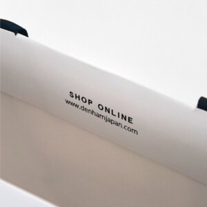 ハサミのロゴと公式URLを口折り部分にデザイン。情報伝達も兼ね備えたプレミアムデニムブランドのオリジナル紙袋