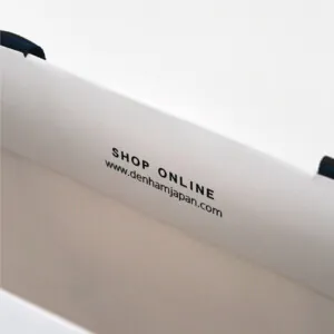 ハサミのロゴと公式URLを口折り部分にデザイン。情報伝達も兼ね備えたプレミアムデニムブランドのオリジナル紙袋