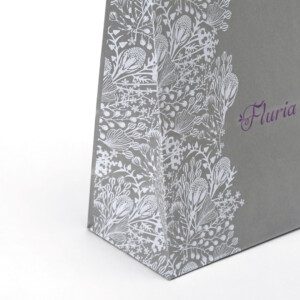 白いボタニカル柄とロゴが映える、グレーのオリジナル紙袋